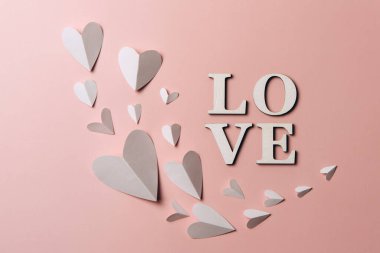 Kağıt kalpli yumuşak renkli arka planda yaratıcı düz sözcük sevgisi. 