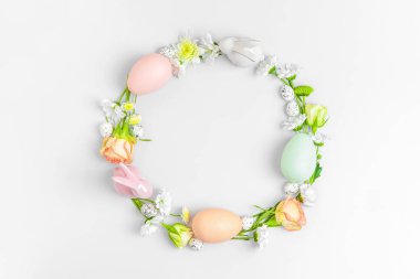 Pastel arka planda çiçeklerin ve paskalya yumurtalarının yaratıcı yerleşimi