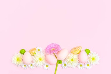 Pastel arka planda çiçeklerin ve paskalya yumurtalarının yaratıcı yerleşimi