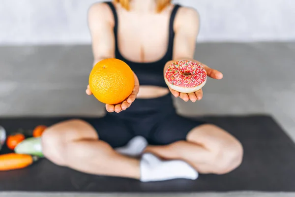 Sportief Vrouwtje Met Donut Sinaasappel Handen Gezond Ongezond Voedselconcept — Stockfoto
