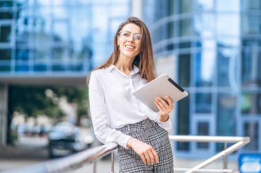 Modern iş merkezinin yakınında tablet kullanan bir iş kadını