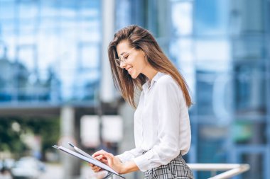 Modern iş merkezinin yakınında tablet kullanan bir iş kadını