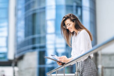 Modern iş merkezinin yakınında tablet kullanan bir iş kadını