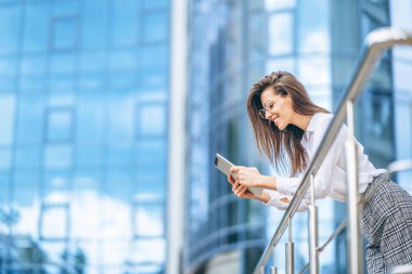 Modern iş merkezinin yakınında tablet kullanan bir iş kadını