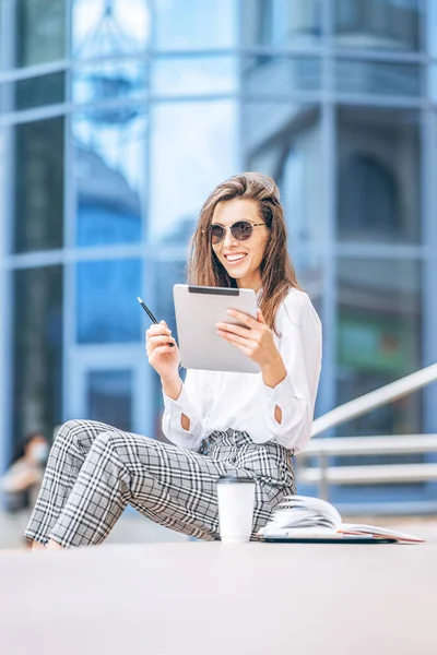 İş merkezinin yakınındaki tablette çalışan genç bir iş kadını.