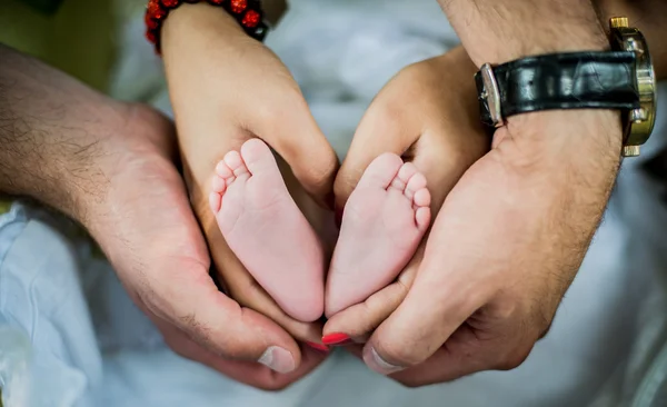 Happy family, parents hands with baby feet