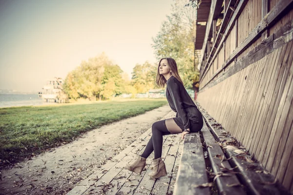 Mooi meisje, zittend op een bankje in het park — Stockfoto