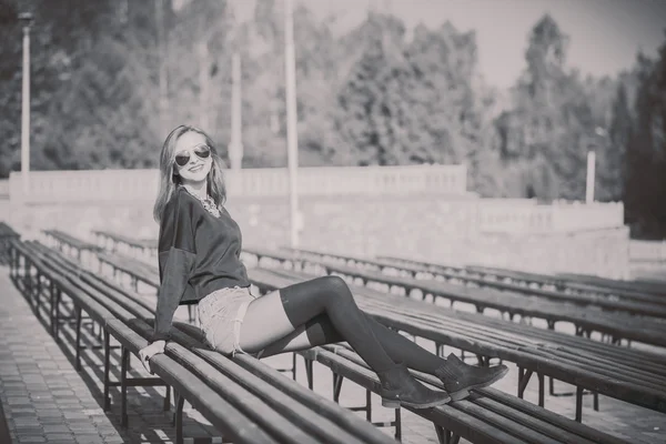 Hezká dívka sedící na lavičce v parku — Stock fotografie