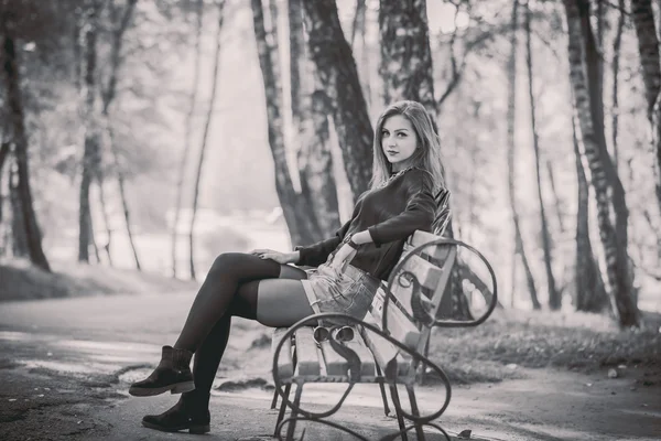 Jeune jolie fille assise sur un banc dans le parc — Photo