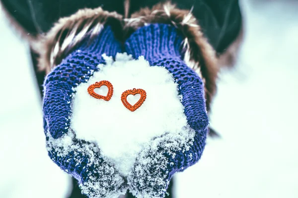 Coração de madeira vermelho nas mãos com neve — Fotografia de Stock