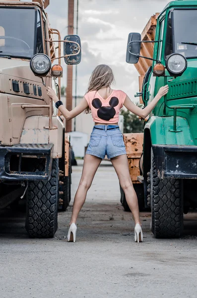 Девушка возле грузовиков в синих шортах — стоковое фото