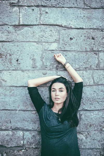 Flicka med långt svart hår nära vägg — Stockfoto