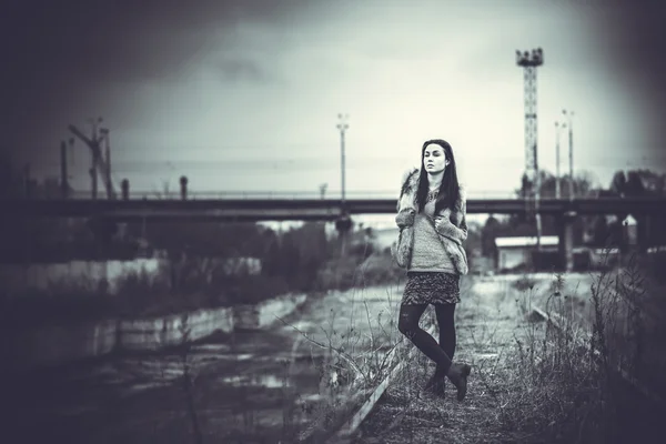 Lange haren brunette meisje buiten met oude industriële brug behin — Stockfoto