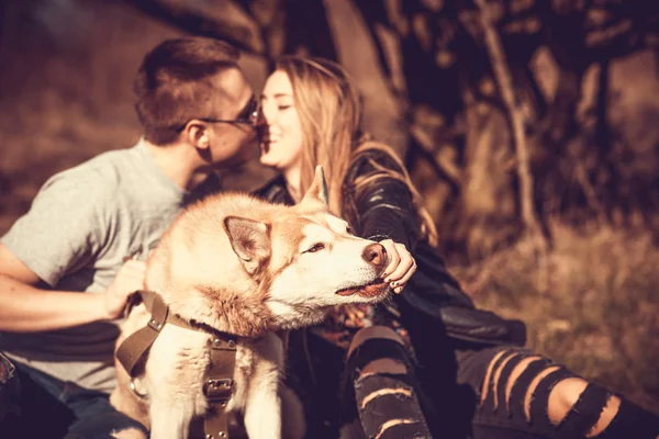 Portrait de chien husky en plein air avec un couple embrassant derrière — Photo