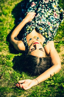 Güzel esmer kadın parkta te çimenlerin üzerinde rahatlatıcı