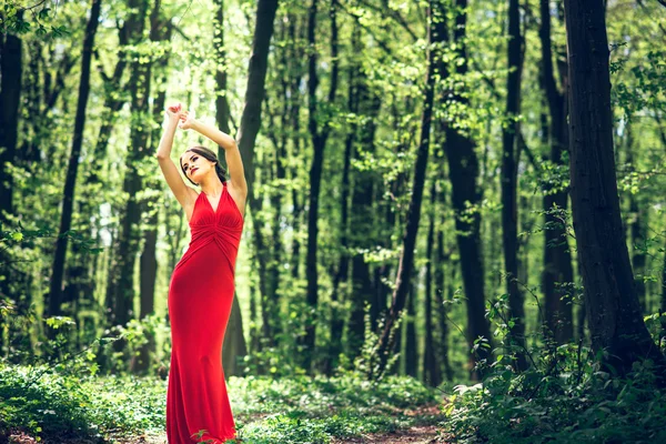 Žena v dlouhé červené šaty, procházky v lese — Stock fotografie