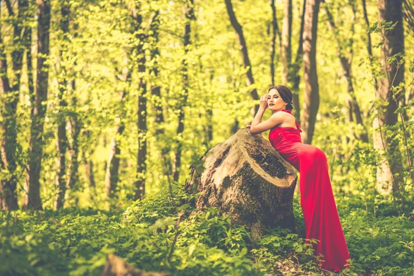 Vrouw in lange rode jurk wandelen in het woud — Stockfoto