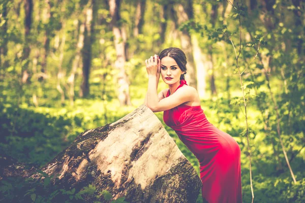 Frau im langen roten Kleid spaziert durch den Wald — Stockfoto