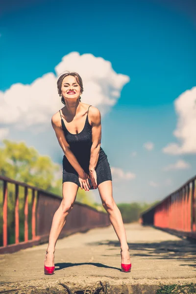 Pretty woman in short black dress on the bridge — Stock Photo, Image