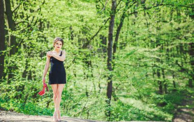 Barefoot brunette girl in black dress outdoor clipart
