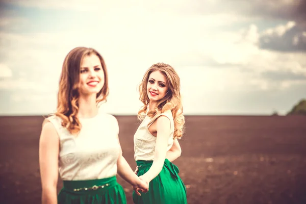 Belle ragazze all'aperto a piedi nel campo, tenendosi per mano — Foto Stock