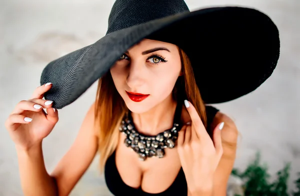 Jovem mulher bonita na praia em chapéu preto — Fotografia de Stock