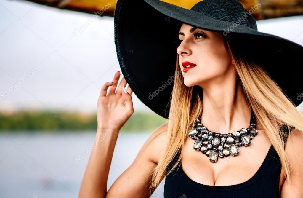 Young pretty   woman on the beach in black hat