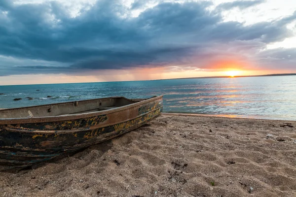 Rusty row boat on the sand at sunset