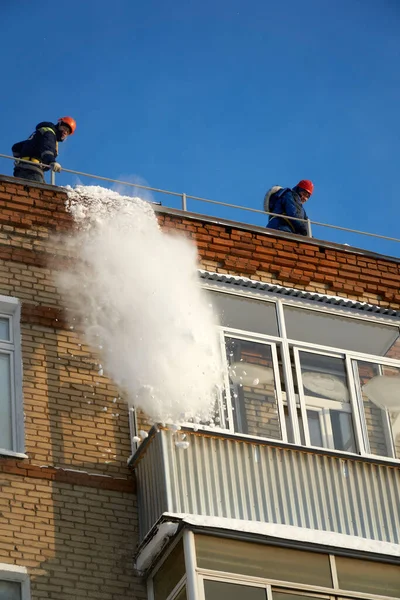 Utility workers remove snow from the roofs of Moscow houses in winter