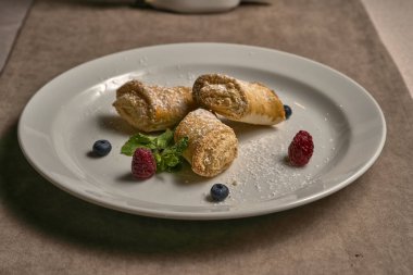 Taze böğürtlenlerle süslenmiş kremalı börekler.