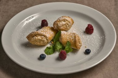 Taze böğürtlenlerle süslenmiş kremalı börekler.