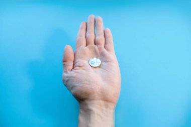 Bir adam avucunun içinde bir sikke tutar, yakın plan. Elinde iki Çek kronu var, POV. İflas, yoksulluk, düşen gelir, düşük maliyet. Mavi arkaplan