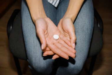 Kadın elinde bir hap tutuyor. Genç bir kadın ilaç almak üzere. Kırpılmış