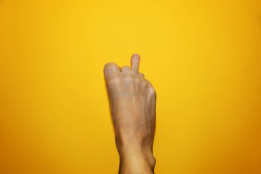 Middle finger on the leg, an offensive gesture. Funny concept Fuck you. The male foot shows the sign Fuck you. Top view on a yellow background.