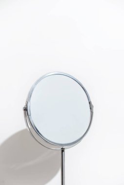 Beyaz arka planda yuvarlak makyaj aynası. Minimalizm dikey fotoğraf.
