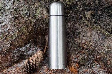 Çelik matara, ormanda dikilip durmak için. Seyahat konsepti, piknik, macera