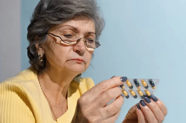 眼鏡をかけた高齢女性は 薬の指示を読もうとしています クローズアップ 治療の概念 病気の退職 — ストック写真