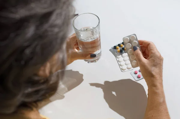 薬を飲んでいる高齢女性 女性の手の水や錠剤のガラスを保持し 後ろからのビューを閉じます 治療の概念 病気の退職 — ストック写真
