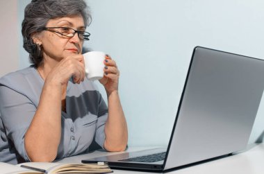 Gözlüklü son sınıf öğrencisi evde ders çalışıyor. Laptopta kahve içen yaşlı bir kadın. Seyahat, serbest çalışma, emeklilik kavramı.