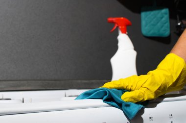 Sarı eldivendeki kadın eli gaz sobasının yüzeyini siliyor, yakın plan. Uzayı kopyala Kimyasal spreyli ev temizliği kavramı.