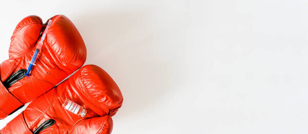 Шприц и ампула допинга на красных боксерских перчатках. Баннер, скопируй пространство. Концепция допинга, фармакологии и спорта.