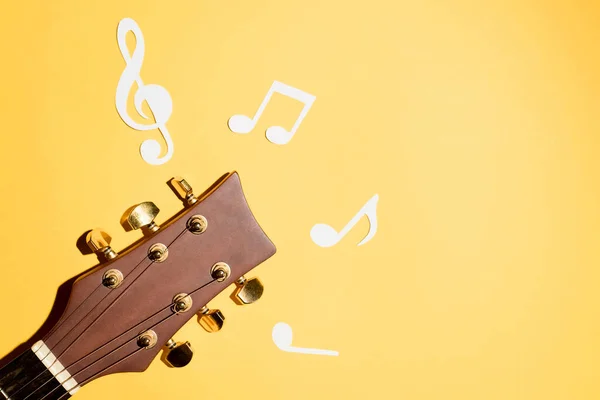 Müzik notaları ve gitar fretboard 'u yakın, düz sarı zemin üzerinde yatıyordu. Müzik arkaplanı
