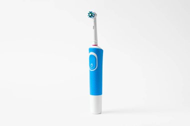Beyaz arka planda duran modern elektrikli diş fırçası. Günlük oral bakım için kontrollü araç.