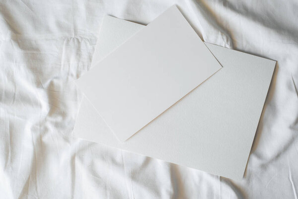 Two blank sheets of paper lying on the fabric, top view. Layout with copy space