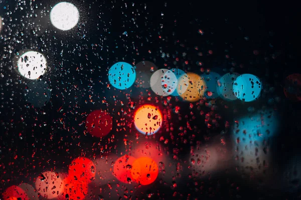 Bokeh rainy night city defocus, raindrops on the window. Abstract background night city life