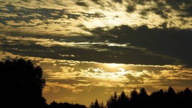 Yuvarlak güneşli güzel gün batımı manzarası ve gökyüzündeki renkli bulutlar.