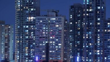 Geceleri gökdelenlerdeki ışık pencereleriyle dolu modern şehir gece manzarası.