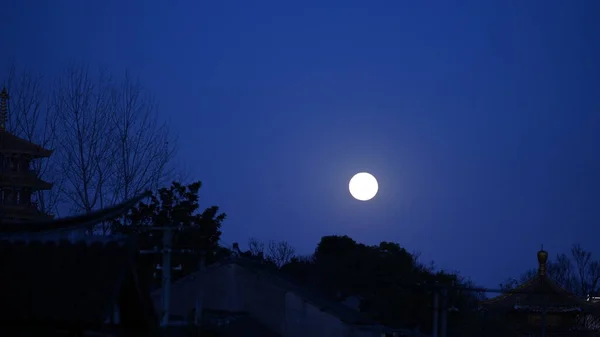 The beautiful moon night view with the round moon and classical Chinese architecture as background