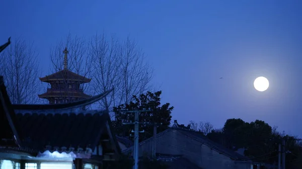 The beautiful moon night view with the round moon and classical Chinese architecture as background