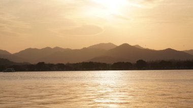 Güzel gün batımı manzarası, kışın gölün yanındaki suyun yansıması.